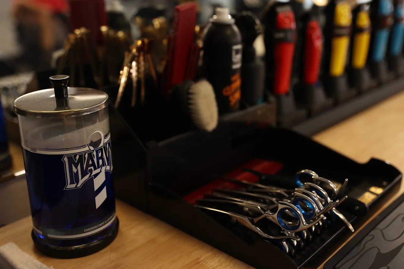 Shears, combs, clippers and a Marvy disinfectant jar laid out on the barber counter at The Garage